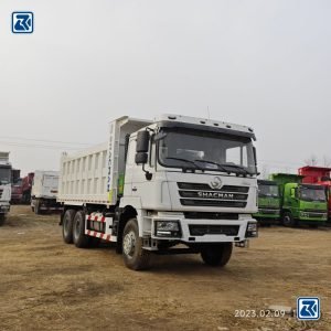 Vista frontal del camión volquete Shacman F3000 6X4: robusto conjunto frontal y potente compartimento del motor.